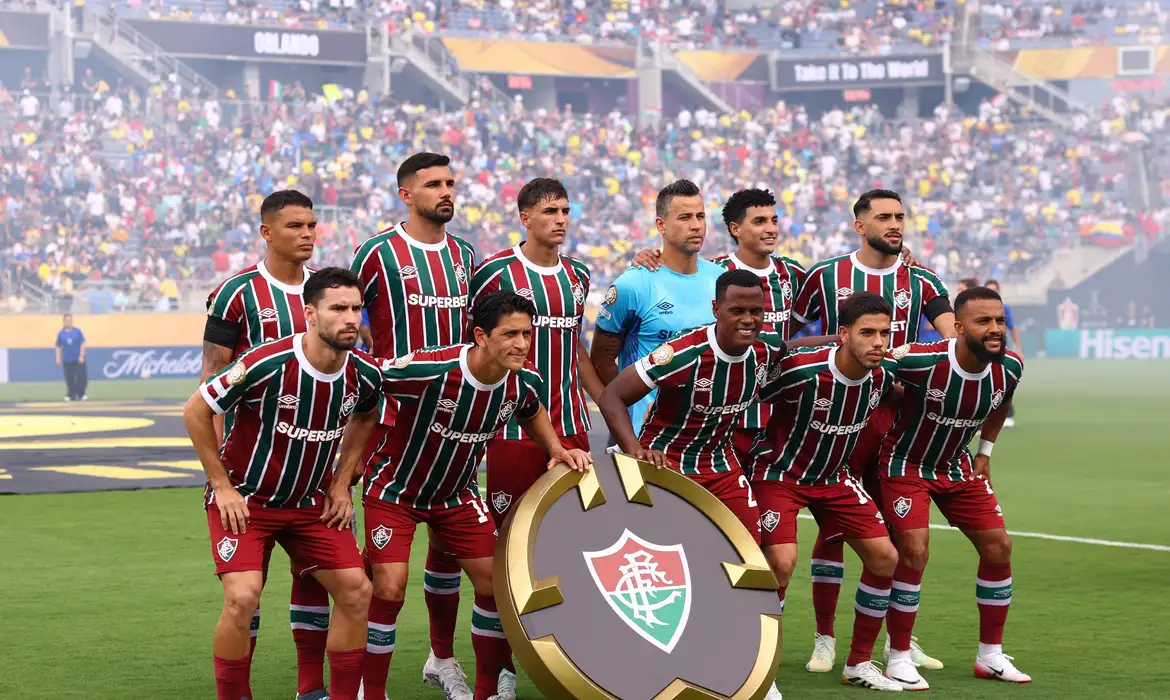 Único time brasileiro nas semifinais do Mundial de Clubes da Fifa, nos Estados Unidos, o Fluminense encara o Chelsea (Inglaterra) na tarde desta terça-feira (08), em Nova Jersey, pela classificação inédita à decisão do título. O jogo no MetLife Stadium, com capacidade para 82,5 mil torcedores, terá início às 16h (horário de Brasília). Mudanças para a semifinal O Tricolor carioca, comandado pelo técnico Renato Gaúcho, entra em campo com ao menos duas modificações em relação ao time que venceu o Al-Hilal (2 a 1) na última sexta (04). O lateral-esquerdo Freytes e o volante Martinelli estão suspensos por terem levado o segundo cartão amarelo no último jogo. O treinador deve optar pelo canhoto Renê na lateral-esquerda e pelo volante Hércules no meio-campo. O jovem piauiense foi decisivo nos jogos anteriores (Inter de Milão e Al-Hilal), quando balançou as redes ao deixar o banco de reservas no segundo tempo. Nesta terça, Hercules pode começar a partida contra o Chelsea como titular do Tricolor. Outra dúvida de Renato Gaúcho recai sobre o lateral-direito Samuel Xavier, que sentiu dores musculares que o obrigaram a sair de campo no final do segundo tempo contra o Al-Hilal. Guga é um dos mais cotados para substituí-lo na posição. Sigilo na escalação Em entrevista coletiva na segunda (07), Renato Gaúcho preferiu não revelar o esquema tático, mas elencou alguns cuidados que o time deve ter em campo contra a equipe britânica. "É um jogo de xadrez. Estudei bastante o adversário, da mesma forma que eu tenho certeza que eles estudaram o Fluminense. Será um jogo de paciência, você não pode se jogar para dentro do adversário nos primeiros minutos, como temos jogado essa Copa do Mundo", afirmou Renato. Renato Gaúcho também expressou sua preocupação com a qualidade técnica do esquema de jogo adotado pelo adversário de hoje. "É muito perigoso, justamente pelo esquema que o Chelsea usa durante as partidas. Então, nós vamos tomar nossos cuidados e é lógico que vai ser muito importante ter a posse de bola, principalmente no horário do jogo, com um calor insuportável. Se se você ficar correndo atrás do adversário, se você não tiver essa posse, o desgaste é muito grande. Então vamos procurar neutralizar as principais jogadas do adversário. Quando ficar com a bola, jogar", finalizou o técnico do tricolor carioca. Campanha do Fluminense no Mundial de Clubes da Fifa O Fluminense fez a melhor campanha no Mundial entre as quatro equipes brasileiras – Botafogo, Flamengo e Palmeiras ficaram pelo caminho. Uma vitória simples contra o Chelsea garante o time carioca na grande final, no próximo domingo (13), contra o vencedor da outra semi - Paris Saint-Germain e Real Madrid se enfrentam na quarta (9). Em caso de empate nos 90 minutos, haverá prorrogação e, se persistir a igualdade no placar, a classificação será definida em cobrança de pênaltis. Desfalques do adversário Do lado do Chelsea, o treinador italiano Enzo Maresca também não poderá contar com todo o elenco. Além do centroavante Liam Delap e do zagueiro Levi Colwill, que cumprirão suspensão por terem recebido o segundo amarelo no duelo contra o Palmeiras, o meia-atacante Romeo Lávia segue lesionado. A boa notícia é que atacante brasileiro João Pedro, recém-contratado pelos Azuis, deve começar jogando no lugar de Delap. Outro reforço será o meio-campista equatoriano Moisés Caicedo, que cumpriu suspensão contra o Verdão, mas estará de volta entre os tiulares do time britânico nesta terça.
