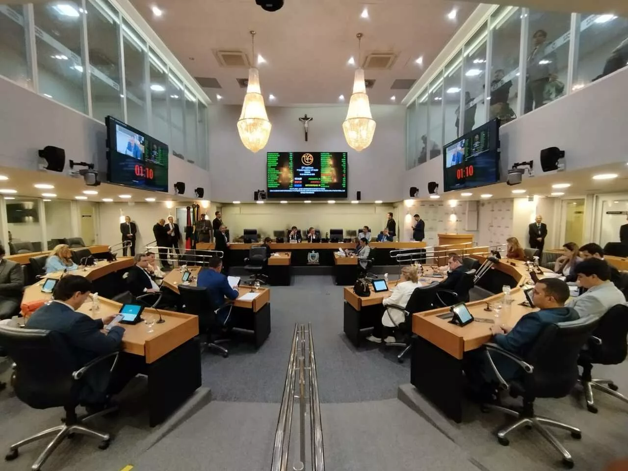 Em decisão proferida nesta quarta-feira (04), o Órgão Especial do Tribunal de Justiça da Paraíba (TJPB) declarou inconstitucional o dispositivo do Regimento Interno da Assembleia Legislativa da Paraíba (ALPB) que estabelecia a invocação religiosa na abertura das sessões ordinárias. A prática previa que o presidente da Assembleia iniciasse as reuniões com a expressão: “Sob a proteção de Deus e em nome do povo paraibano, declaro aberta a presente sessão”. O dispositivo ainda determinava que a Bíblia Sagrada permanecesse sobre a mesa diretora durante todo o Pequeno Expediente, fase que marca o início das sessões ordinárias. O entendimento do tribunal foi firmado no âmbito de uma Ação Direta de Inconstitucionalidade (ADI) ajuizada pelo Ministério Público da Paraíba (MPPB). Para o MPPB, o dispositivo que determinava a invocação religiosa viola princípios constitucionais, entre eles a laicidade do Estado, a liberdade religiosa, a igualdade, a impessoalidade e a neutralidade do poder público em relação às crenças. Os votos no julgamento A desembargadora Fátima Bezerra, relatora do caso, votou inicialmente pela improcedência da ação. Contudo, após o voto do desembargador Ricardo Vital, ela reviu seu entendimento. Ao final, a maioria do colegiado acompanhou a posição adotada. Para Ricardo Vital, a norma afronta a laicidade do Estado ao privilegiar uma crença específica, ao vincular a abertura das sessões à presença obrigatória da Bíblia Sagrada. Segundo ele, o poder público não pode adotar símbolos ou rituais que representem uma religião em detrimento das demais. Houve divergência no colegiado. Os desembargadores Aluízio Bezerra e Onaldo Queiroga votaram contra a maioria, ao argumentarem que o rito tem origem histórica e cultural e que a maior parte da população brasileira se declara católica. Já o desembargador Abrão Lincoln se absteve de votar.