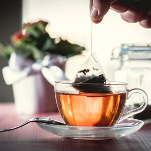 Putting tea bag into glass cup full of hot water